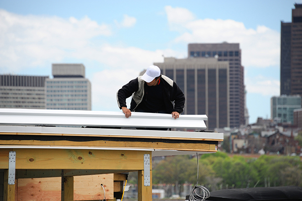 worker repairing the roof with downtown buildings as background